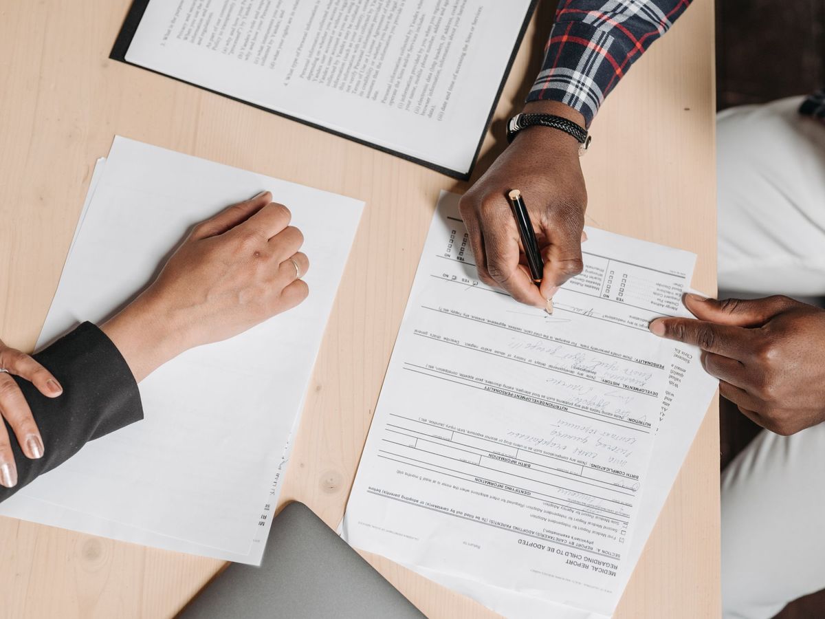 Two people reviewing and signing paperwork at a desk